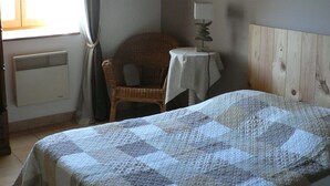 A bedroom with a bed, a chair, a table, a lamp, a picture on the wall, and a window with curtains. - Charming gîte with large swimming pool in the Lot department (CANIAC DU CAUSSE)