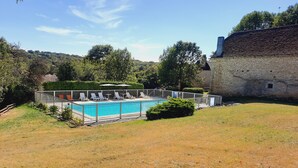 A swimming pool with lounge chairs, surrounded by a stone building and trees. - Charming gîte with large swimming pool in the Lot department (CANIAC DU CAUSSE)