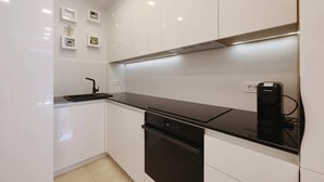 Eine moderne Küche mit weißen Schränken, einer schwarzen Arbeitsplatte und einem eingebauten Backofen.