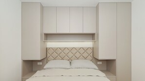 Ein Schlafzimmer mit Bett, Kopfteil und eingebauten Schränken.
