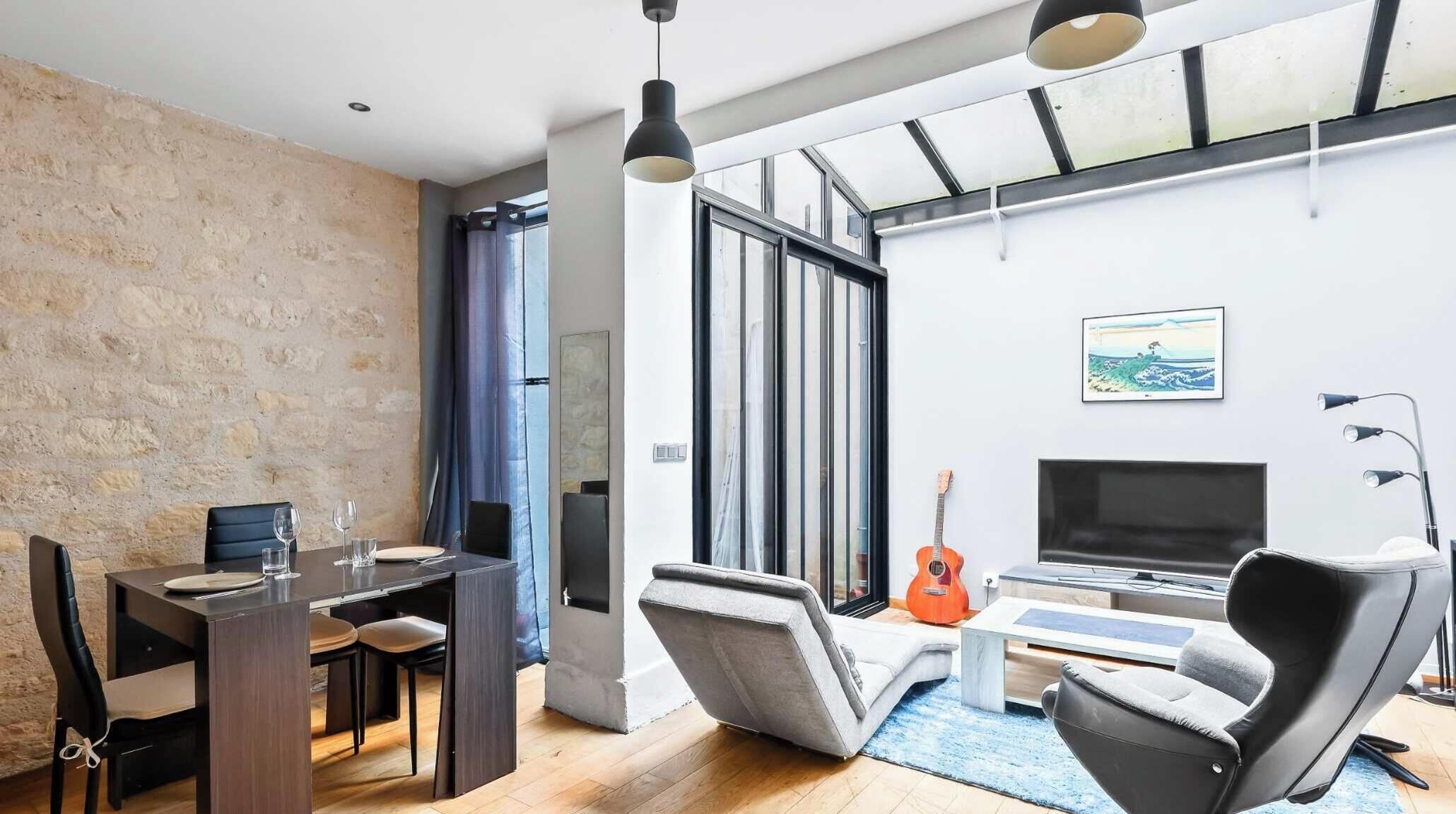 Un salon moderne comprenant un coin repas, un téléviseur et une guitare.