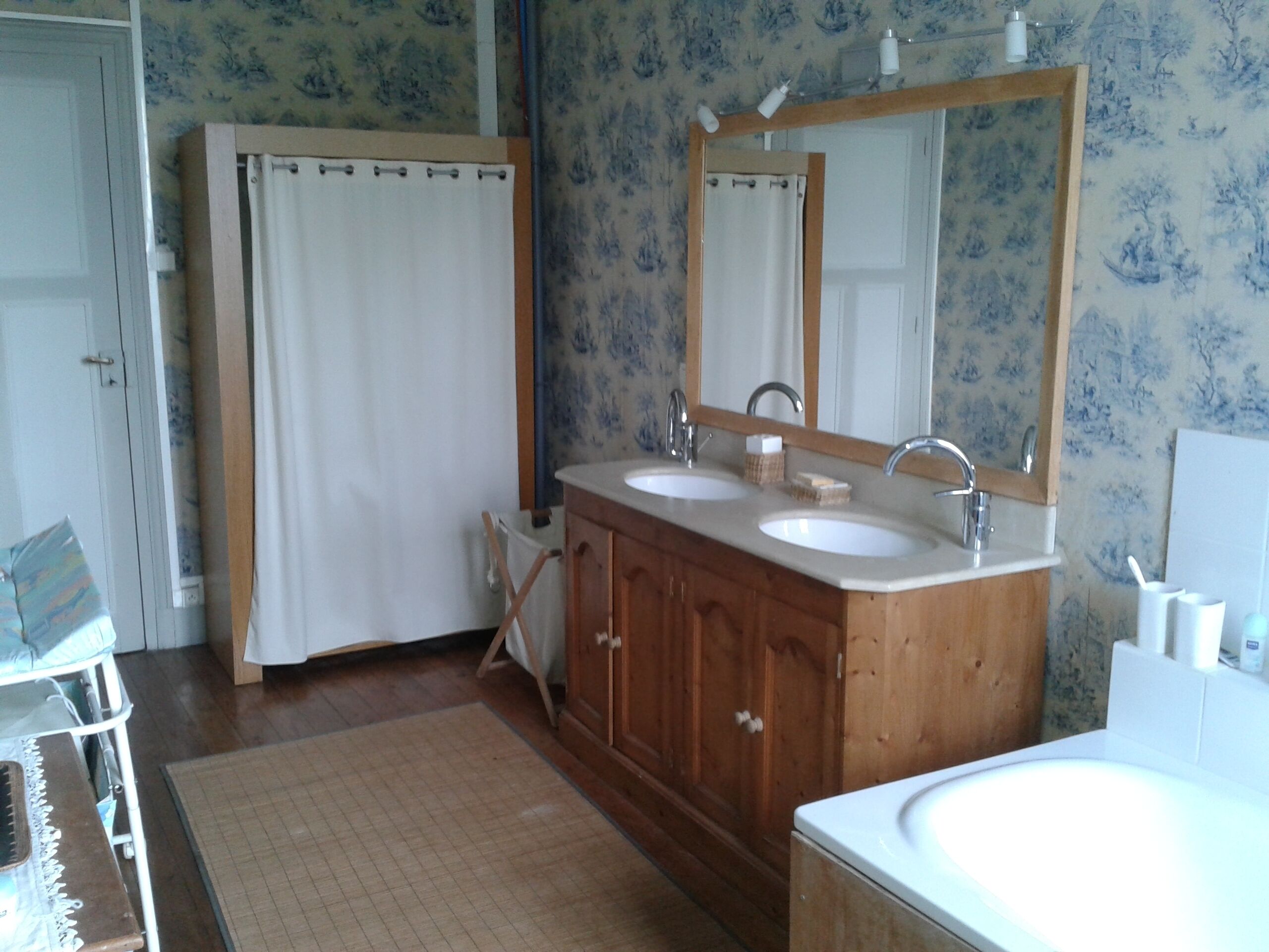A bathroom with wooden cabinets, two sinks, a large mirror, and a shower curtain.