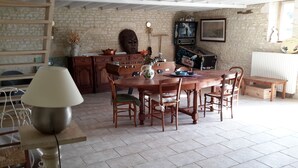 Een rustieke eethoek met een houten tafel en stoelen, een stenen muur en een plafond met zichtbare balken.