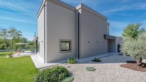 A modern two-story building with a flat roof, large windows, and a well-maintained garden with gravel paths and greenery. - Villa Kalea With Pool (Labin)