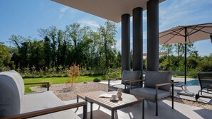 An outdoor patio area with a pool, modern furniture, and a view of a garden. - Villa Kalea With Pool (Labin)