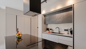 A modern kitchen with a black countertop, white cabinets, a marble backsplash, and a built-in oven. - Villa Kalea With Pool (Labin)