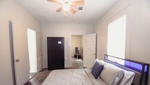 A bedroom with a bed, a ceiling fan, and a door leading to another room.