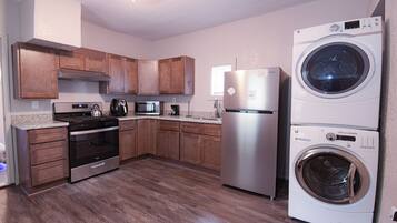 A modern kitchen with wooden cabinets, stainless steel appliances, and a built-in washer and dryer.