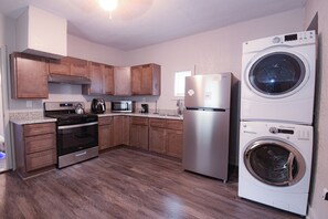 A modern kitchen with wooden cabinets, stainless steel appliances, and a built-in washer and dryer.