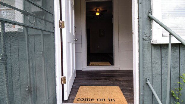 A doorway with a "come on in" mat, a ceiling fan, and a doormat.