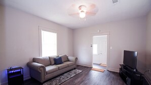 A living room with a sofa, a television, and a ceiling fan.