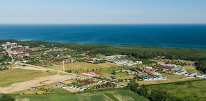 An aerial view of a coastal village with houses, roads, and fields. - Comfortable Holiday Homes Close to the Beach (Darlowo)