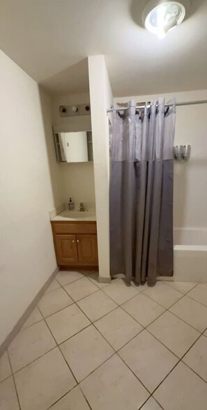 Un baño con cortina de ducha, lavabo y espejo.