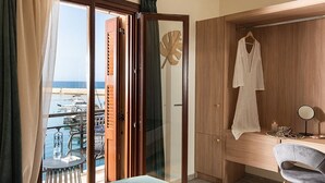 A hotel room with a bed, a desk with a chair, a view of the sea, and an air conditioning unit. - 3 Sails - 2BR on Venetian Harbour  (Chania)