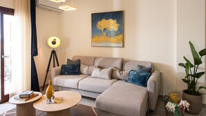 A modern living room with a sofa, a floor lamp, a round coffee table, and a painting on the wall. - 3 Sails - 2BR on Venetian Harbour  (Chania)