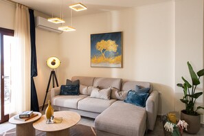 A modern living room with a sofa, a floor lamp, a round coffee table, and a painting on the wall.