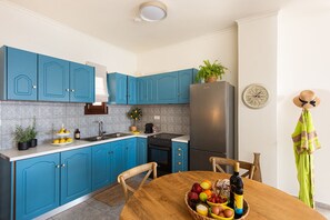 Una cocina moderna con armarios azules, un refrigerador de acero inoxidable y una mesa de madera con una cesta de frutas.