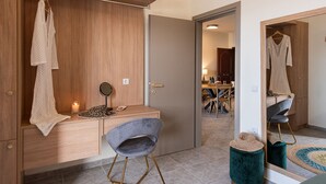 A modern bedroom with a wooden wardrobe, a vanity with a mirror, a grey chair, and a small stool. - 3 Sails - 2BR on Venetian Harbour  (Chania)