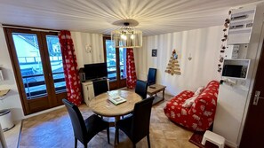 Een knus woongedeelte met een eettafel, stoelen, een bank, een televisie en een open haard.