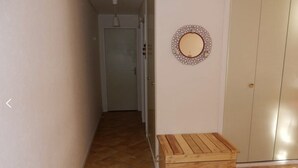 A hallway with a wooden bench, a mirror on the wall, and a door at the end. - Alpine Refuge Near the Forest Road (Mont-Dore)