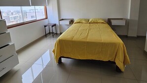 Een slaapkamer met een bed, een bureau en een raam.