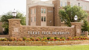 Ein Backsteingebäude mit dem Schild "Texas Tech University" und einer begr ünten Anlage mit Blumen.