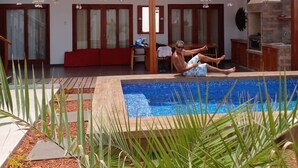 Ett modernt hus med en swimmingpool, en täckt uteplats och ett köksområde.