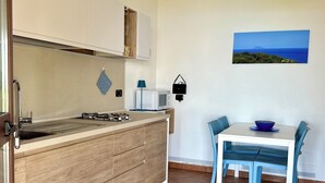 Et lille køkken med træbordplade, mikrobølgeovn og spiseplads med bord og stole.