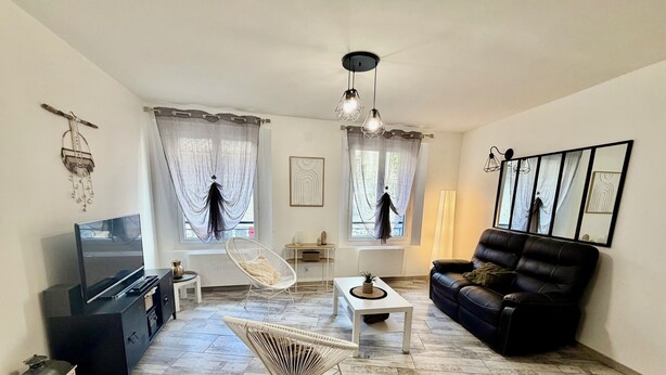 A living room with a TV, a black sofa, a white chair, a coffee table, and a decorative hanging light. - House in the heart of Sisteron (Sisteron)