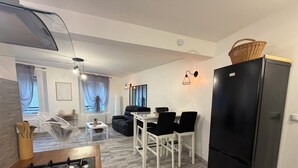 A modern kitchen with a black refrigerator, a dining area with white chairs, and a sofa. - House in the heart of Sisteron (Sisteron)