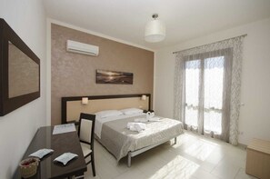 A hotel room with a bed, a desk with papers, a chair, a lamp, and a window with curtains. - Beb Coppola  (Castelluzzo)