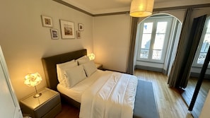 Une chambre à coucher bien rangée, avec un lit, des lampes de chevet et des tableaux encadrés accrochés au mur.