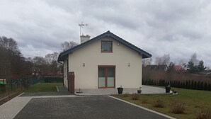Une maison à deux étages avec un toit en pente, une porte d’entrée et une petite fenêtre située au-dessus de la porte.