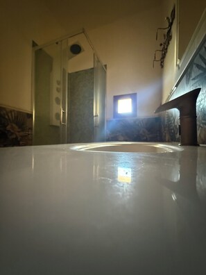A bathroom with a bathtub, a shower, and a window.