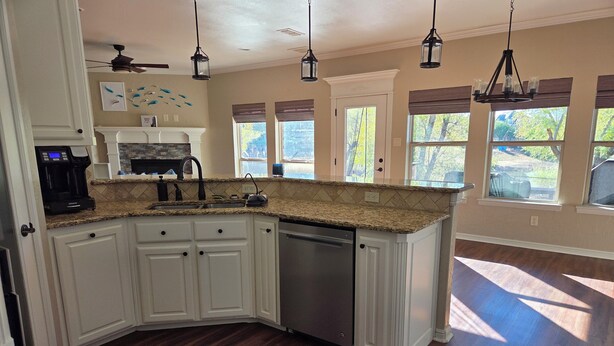 A kitchen with white cabinets, a dishwasher, a coffee maker, and pendant lighting. - On The Pond (Granbury)