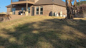 A two-story house with a balcony, a garage, and a well-maintained lawn. - On The Pond (Granbury)
