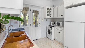 A compact kitchen with a sink, washing machine, microwave, and a refrigerator. - Anthoula's Sea View Apartment (27R5+C6 Piso Livadi)