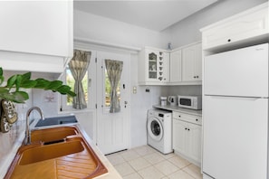 A compact kitchen with a sink, washing machine, microwave, and a refrigerator. - Anthoula's Sea View Apartment (27R5+C6 Piso Livadi)