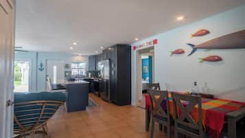 A modern kitchen with dark cabinets, a central island, and a dining area with a table and chairs.
