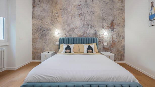 A bedroom with a large bed, a textured wall, bedside tables, and a window. - LUXURY BERGAMO CITY APARTMENTS champagnerie (Bergamo)