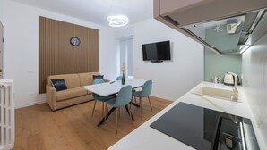 A modern kitchen with a built-in stove, a sink, and a flat-screen TV mounted on the wall. - LUXURY BERGAMO CITY APARTMENTS champagnerie (Bergamo)