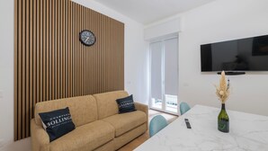 A modern living room with a sofa, a table, a vase, and a wall-mounted TV. - LUXURY BERGAMO CITY APARTMENTS champagnerie (Bergamo)