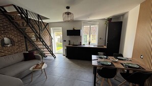 Une cuisine moderne dotée d’un îlot central, d’un coin repas avec une table dressée pour deux personnes et d’un escalier menant à un niveau supérieur.