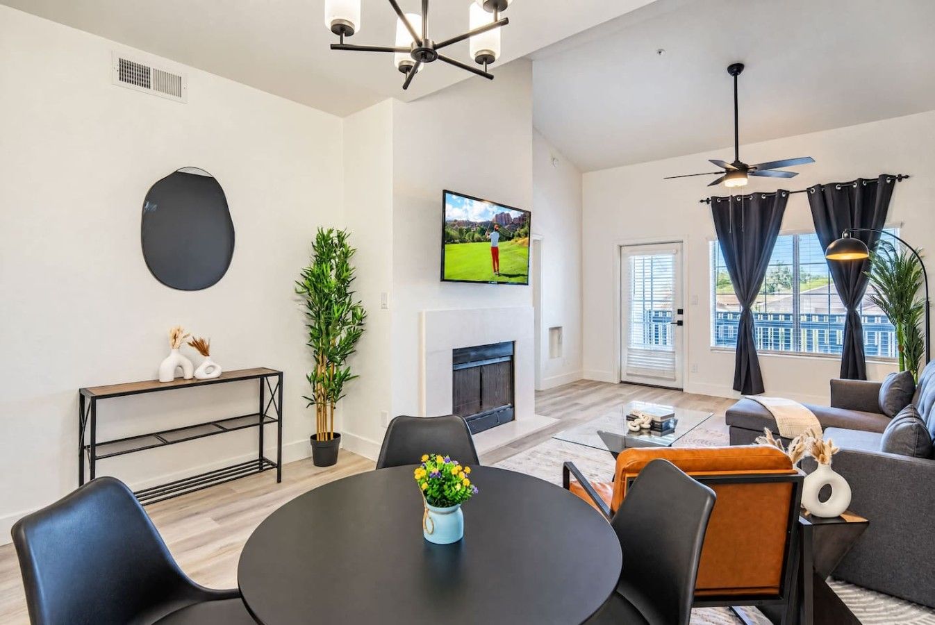 A modern living room with a fireplace, a flat-screen TV, and a dining area with a round table.