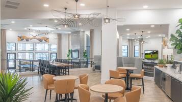 A modern hotel lobby with a dining area, seating arrangements, and a kitchen area.