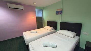 A hotel room with two single beds, a window, an air conditioning unit, and a small painting on the wall.