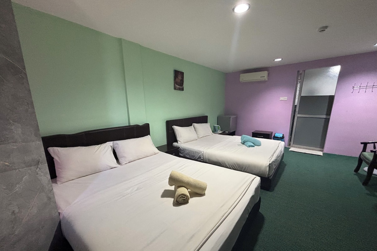 Hotellihuone, jossa on kaksi sänkyä, televisio, ilmastointilaite ja liukuovi.