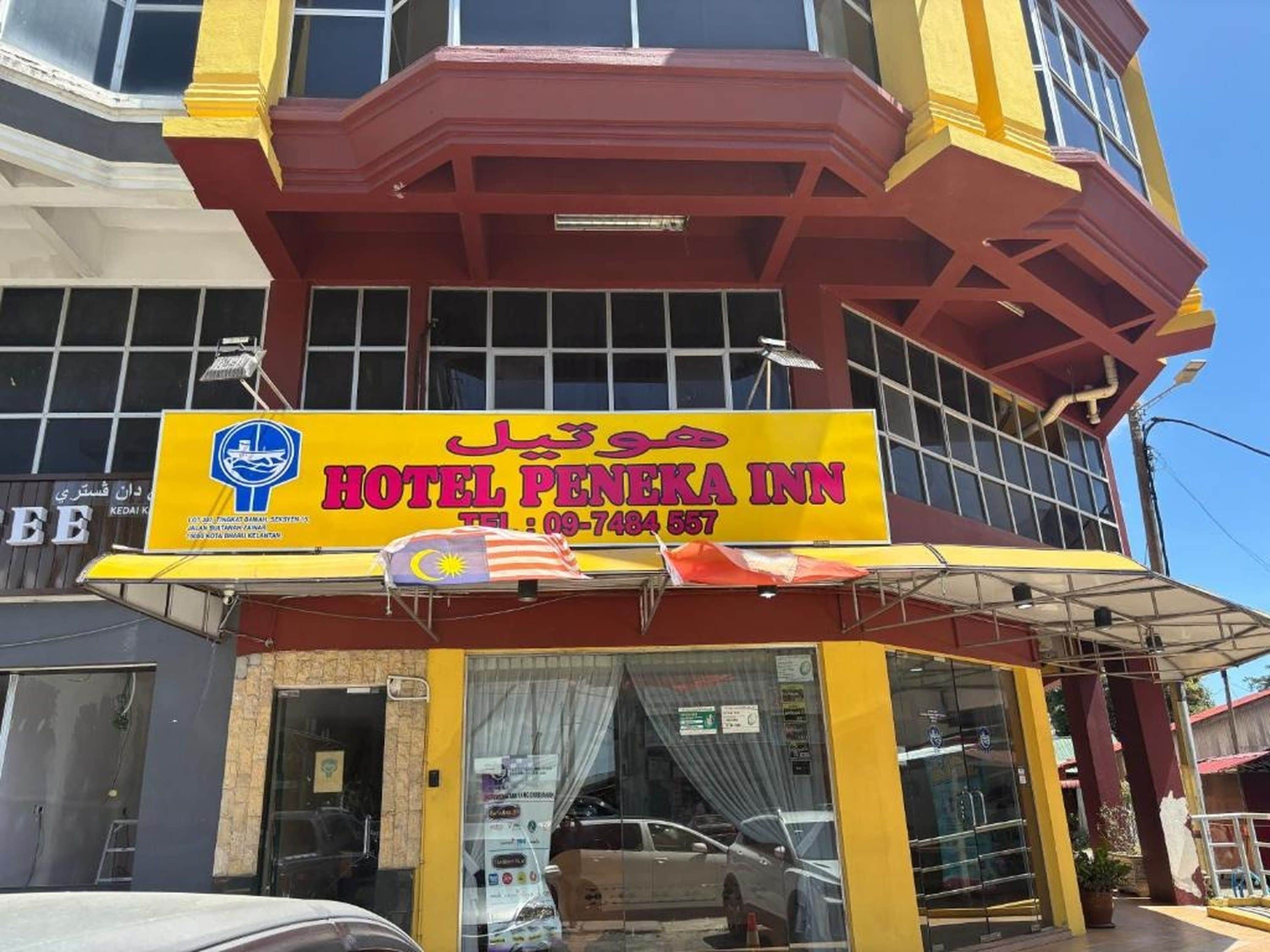 Un hotel con una fachada destacada de color amarillo y rojo, un letrero grande con el nombre del hotel y un número de contacto.