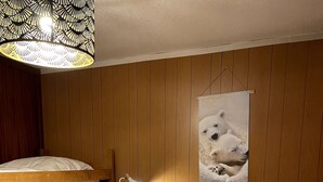 Habitación con literas, cabecera de madera, lámpara de noche y un póster de osos polares.