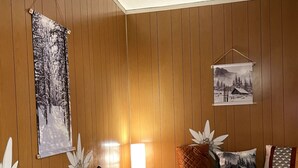 Una habitación acogedora con un revestimiento de madera, un sofá gris, una mesita pequeña y una lámpara.